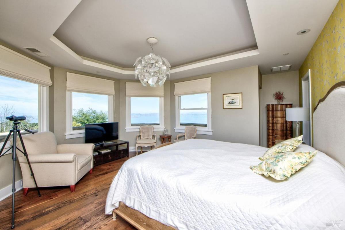 Bedroom with coastal views through multiple windows, featuring a telescope and a reading corner.