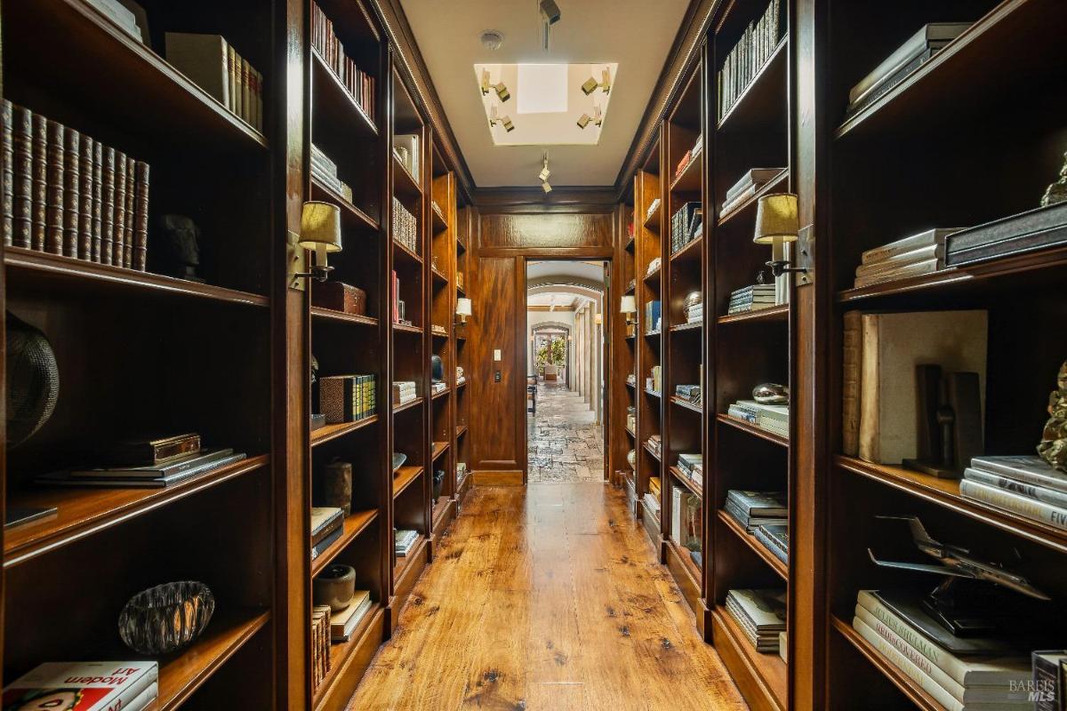 Library hallway with wooden bookshelves and a view into a stone-floored corridor.