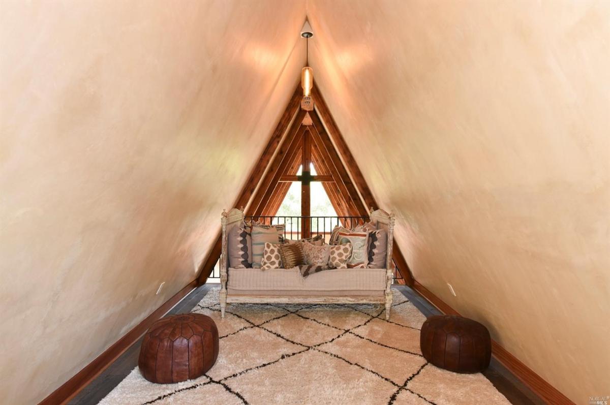 A triangular nook with a daybed and poufs on a patterned rug.