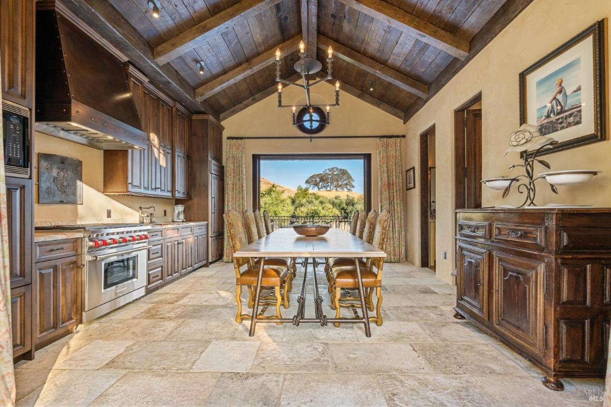 A dining area in a kitchen with wood cabinetry, a dining table, and a large open doorway.