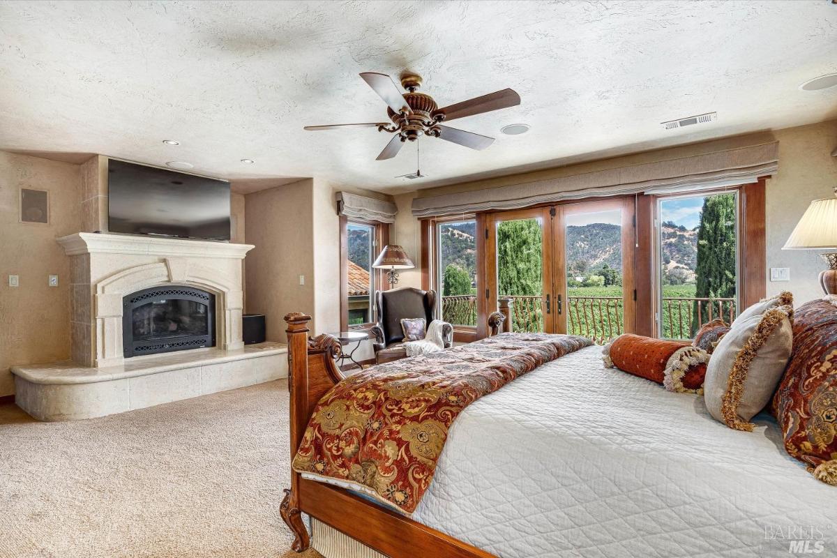 A bedroom with a fireplace, seating area, and balcony access.