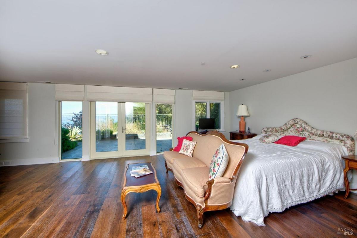 Bedroom with hardwood flooring, French doors leading to a patio, and a sitting area.