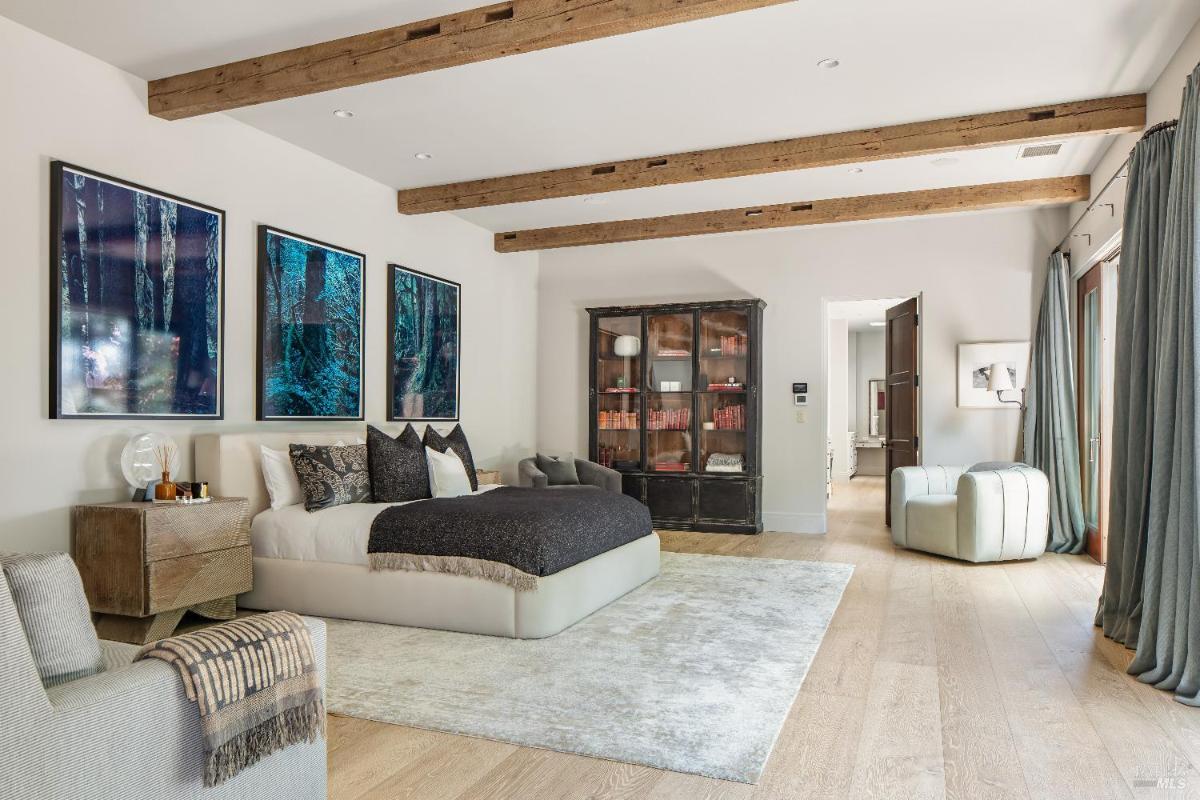 Spacious bedroom with a bed, side table, and wooden beams on the ceiling.