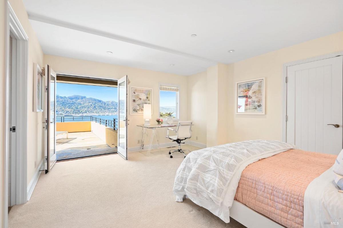 Bedroom features a bright layout with a single bed, built-in workspace, and double doors opening to a terrace with hillside views.