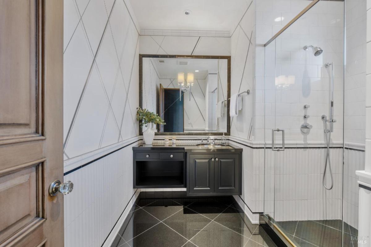 Bathroom with a glass-enclosed shower, double vanity, and warm lighting.