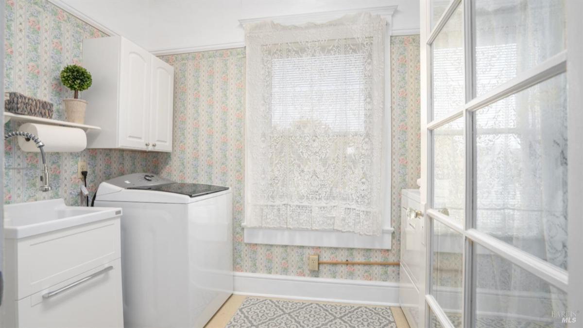 Laundry room with washer, sink, and cabinets.