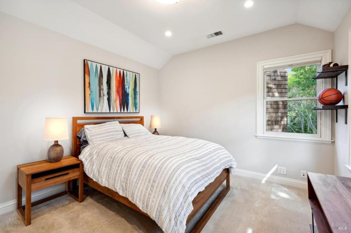 Bedroom with a striped bed, wooden side tables, and a colorful wall art piece.