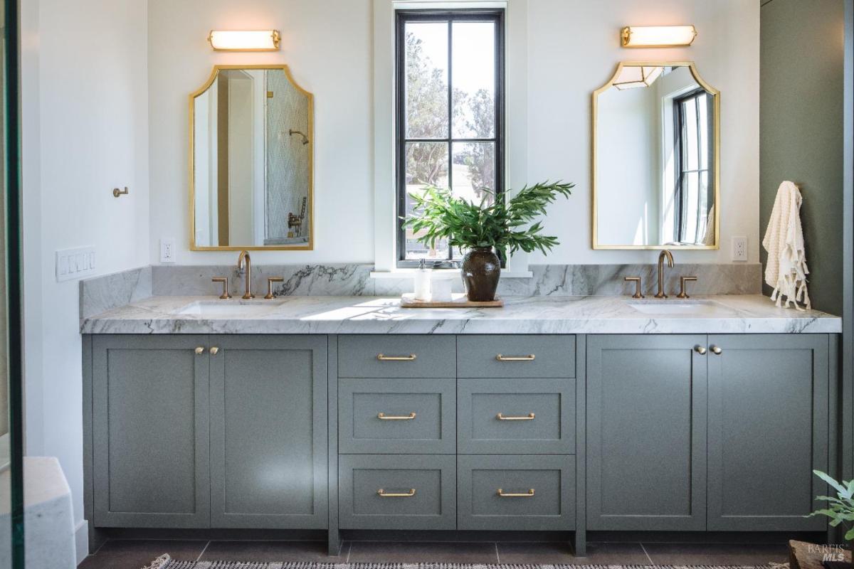 A bathroom with dual sinks, a marble countertop, and large mirrors above.