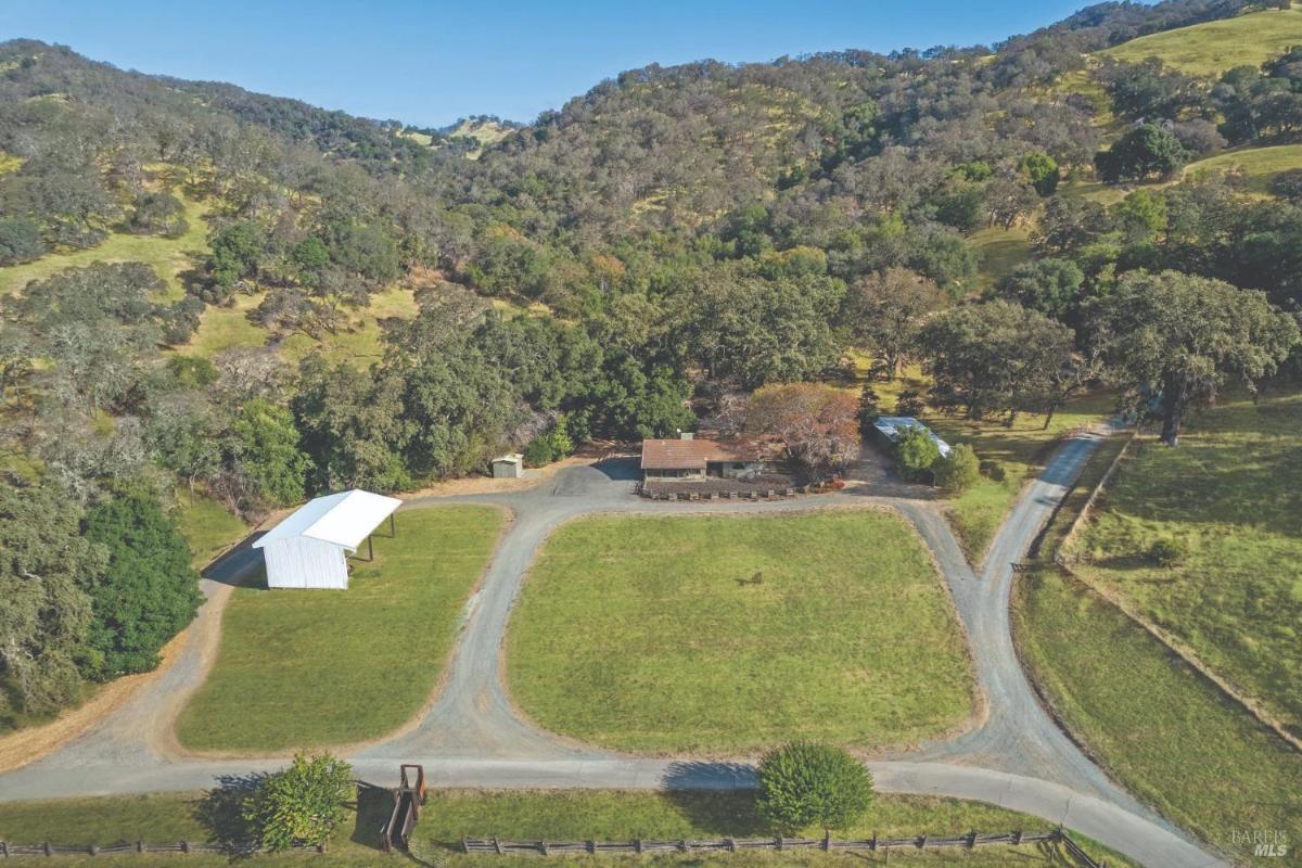 Aerial view of a property with a house, barn, and surrounding greenery.