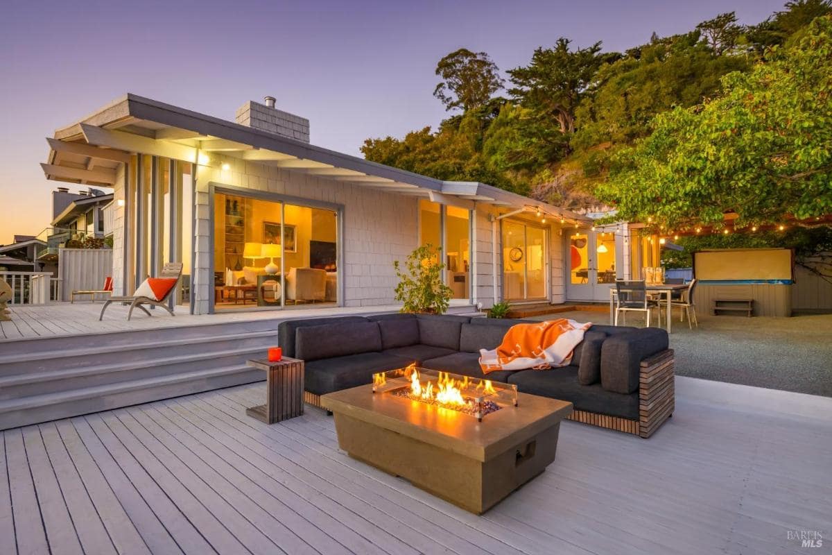 Outdoor deck with firepit seating and house exterior at sunset.