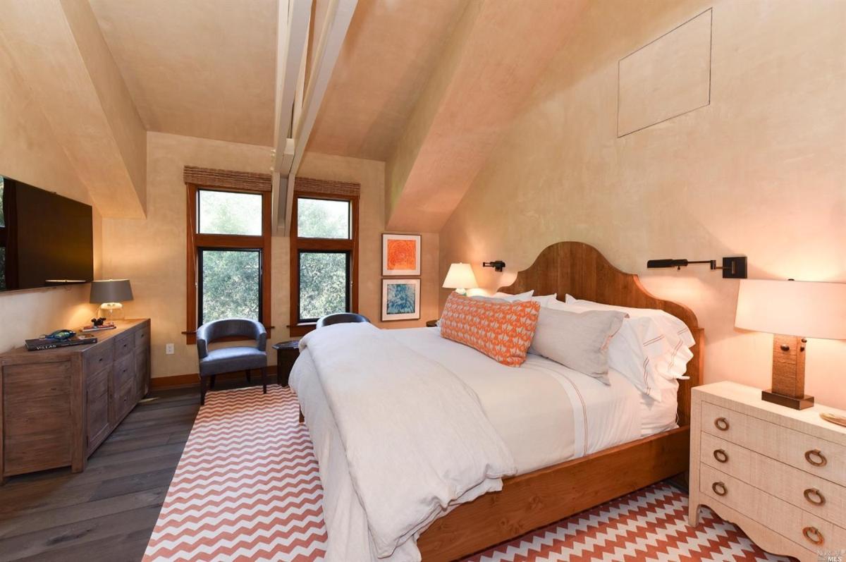 A bedroom with a sloped ceiling, wood furniture, and a zigzag-patterned rug.