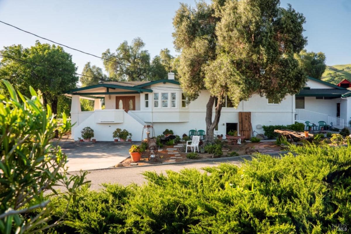 White ranch-style house with trees and patio area.