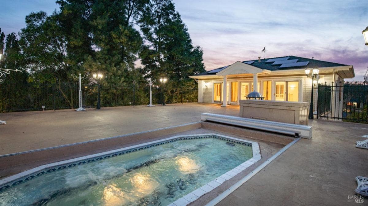 Outdoor hot tub area with lights and patio.