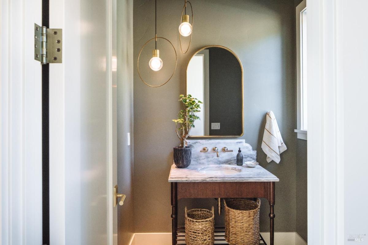 A small bathroom with a single sink, a mirror, and decorative plants.