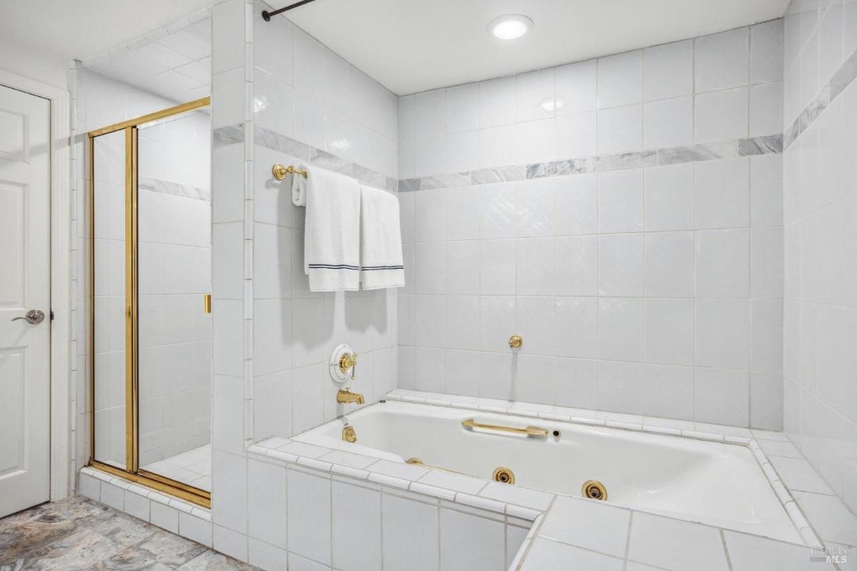 A white-tiled bathroom with a built-in tub and a glass shower enclosure.