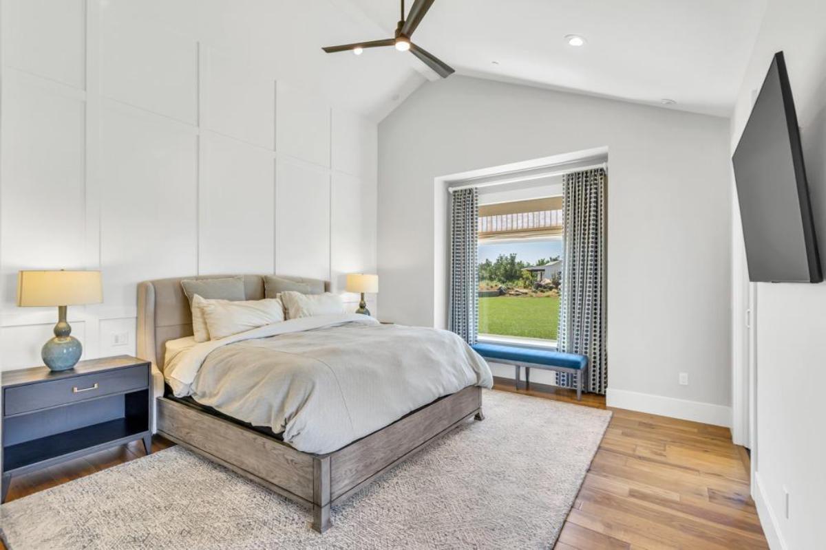 A bedroom featuring a bed, nightstands, lamps, and a window with a view.