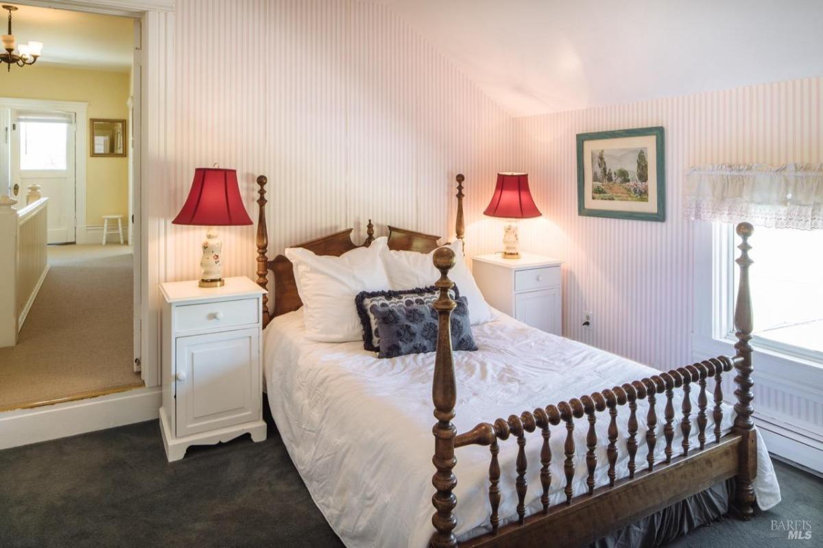 A bedroom with a wooden bed, striped wallpaper, and side tables with lamps.