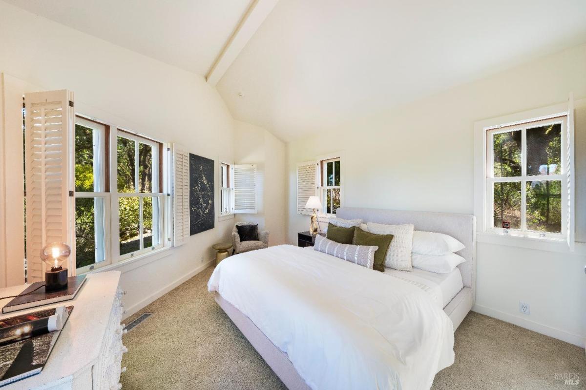 Large bedroom with a bed, seating area, and corner windows.