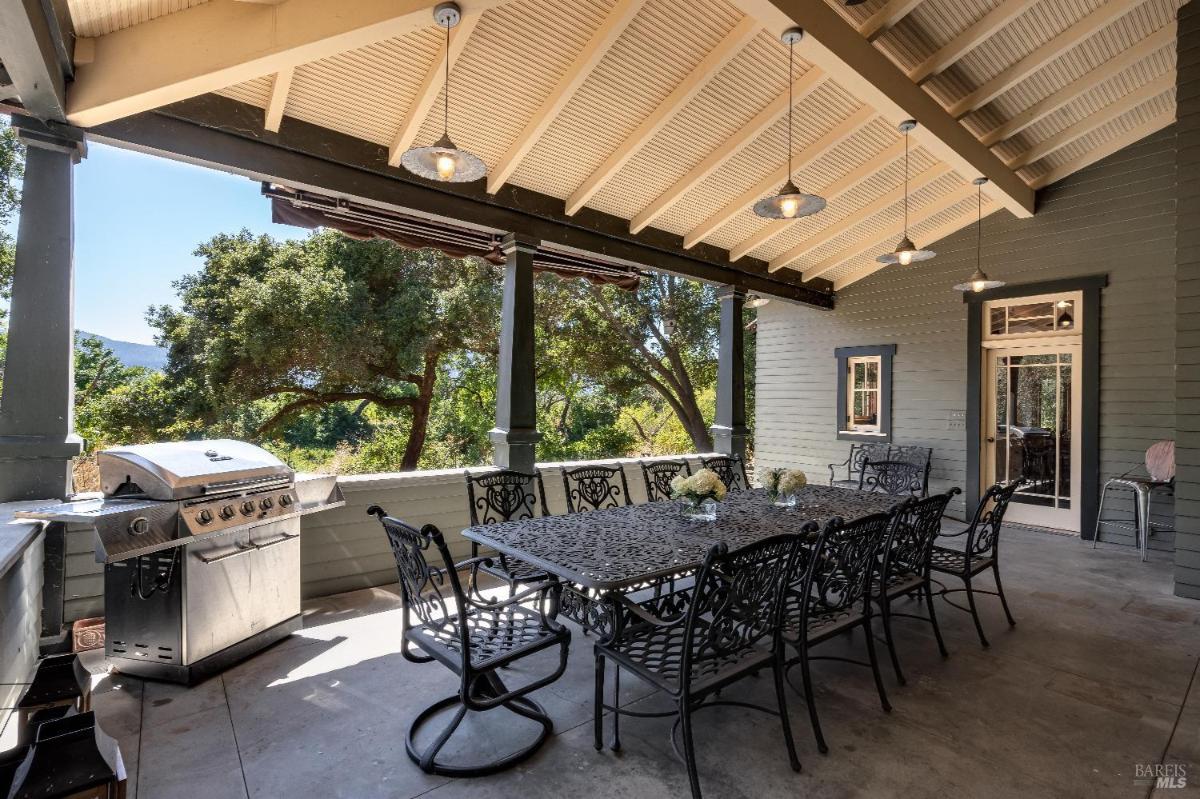 Covered patio with a long dining table, chairs, and a barbecue grill.