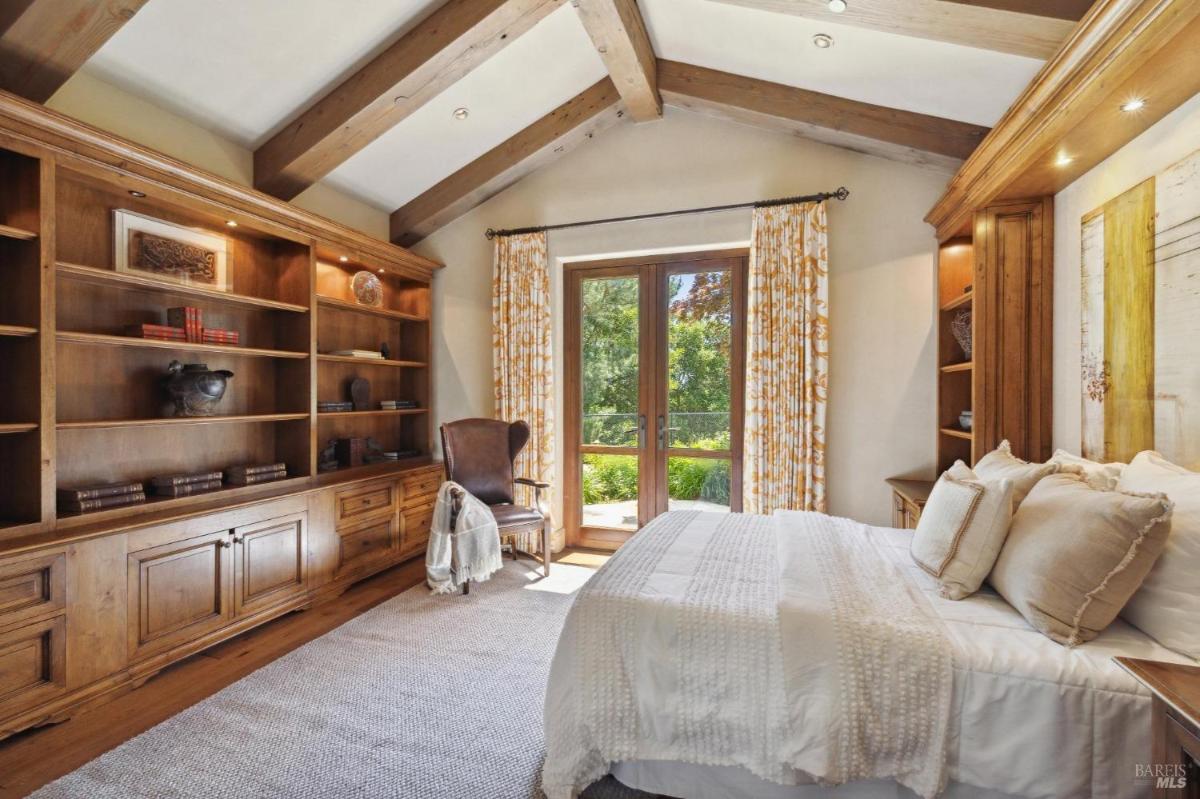 A cozy bedroom with wooden shelves filled with books and decorative items. 