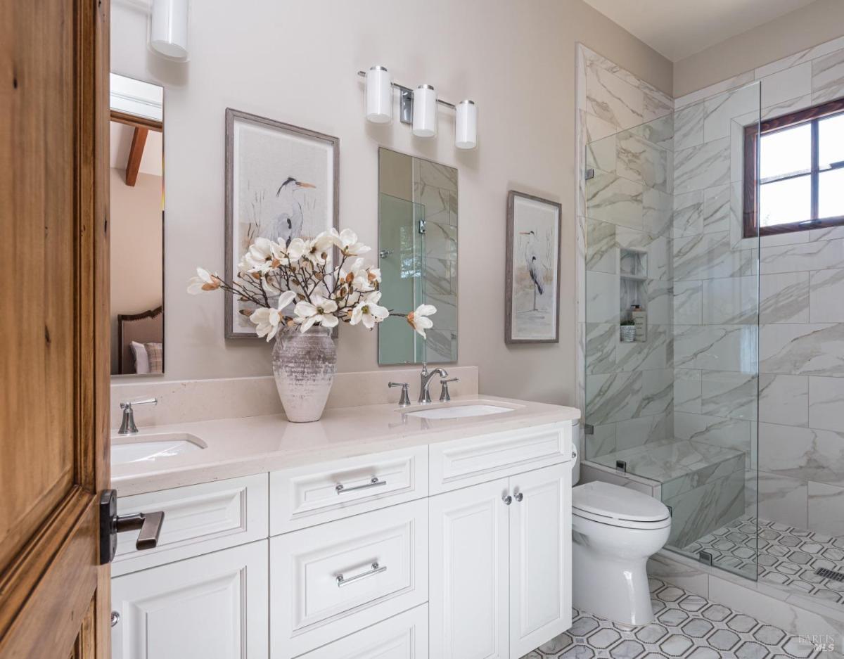 Bathroom with double vanity and glass-enclosed shower.