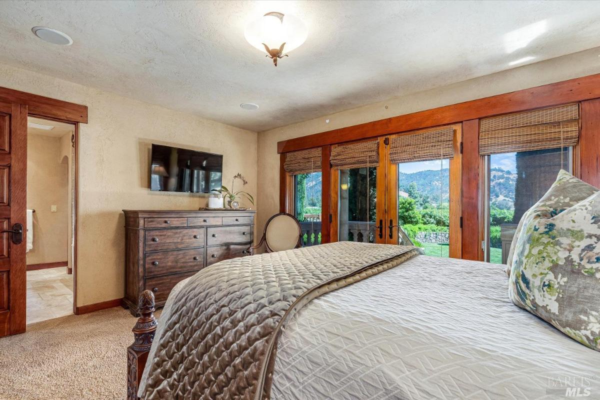 A bedroom with patio access and wood-trimmed windows.