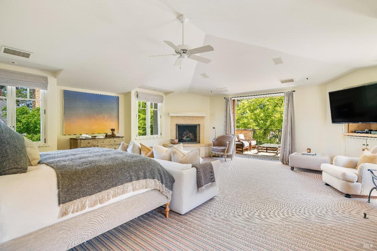 Bedroom featuring a fireplace, seating area, and wide windows with a view.