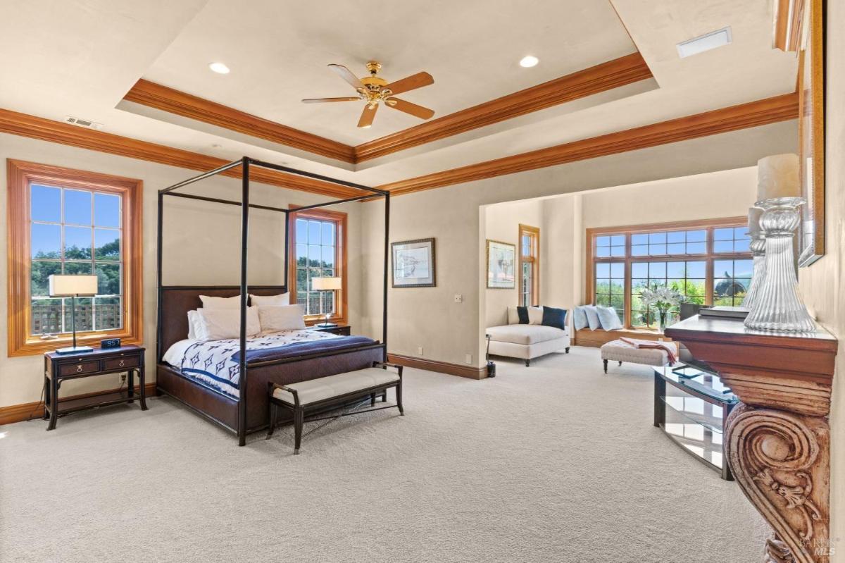 Large bedroom with a four-poster bed, seating area, and wide windows offering scenic views.