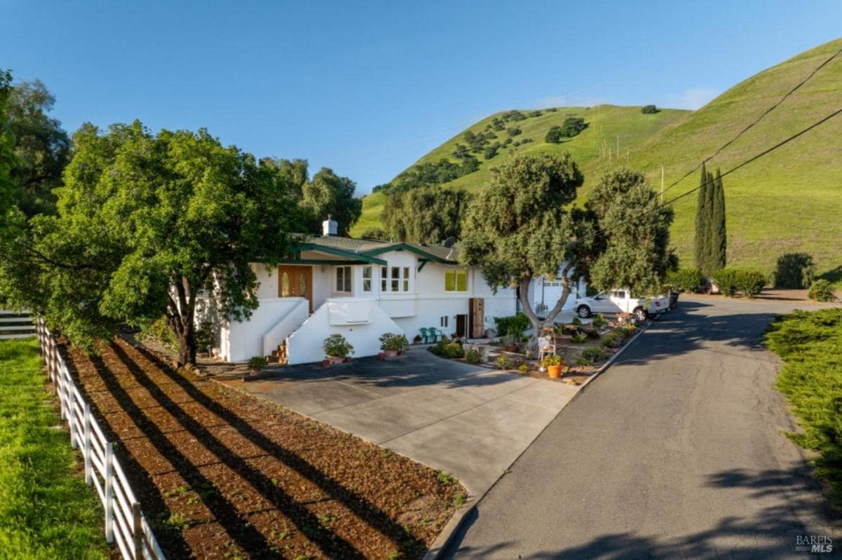 Elevated view of a house with a driveway and surrounding greenery.