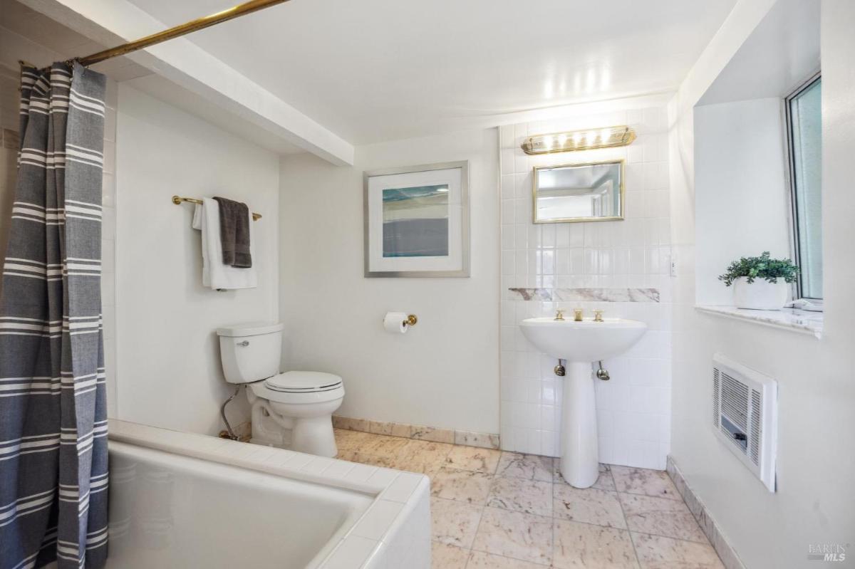 A second bathroom with a white sink, toilet, and a bathtub with a shower curtain.