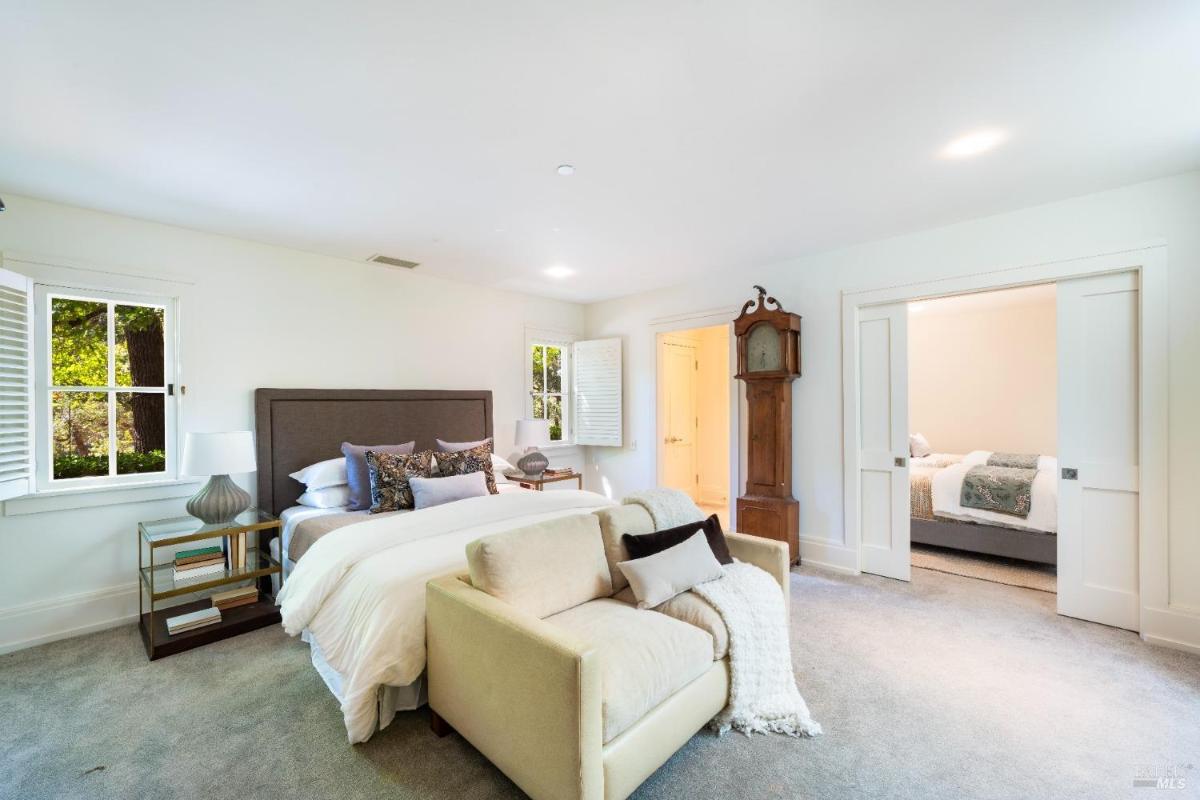 Large bedroom with a bed, seating area, and corner windows.