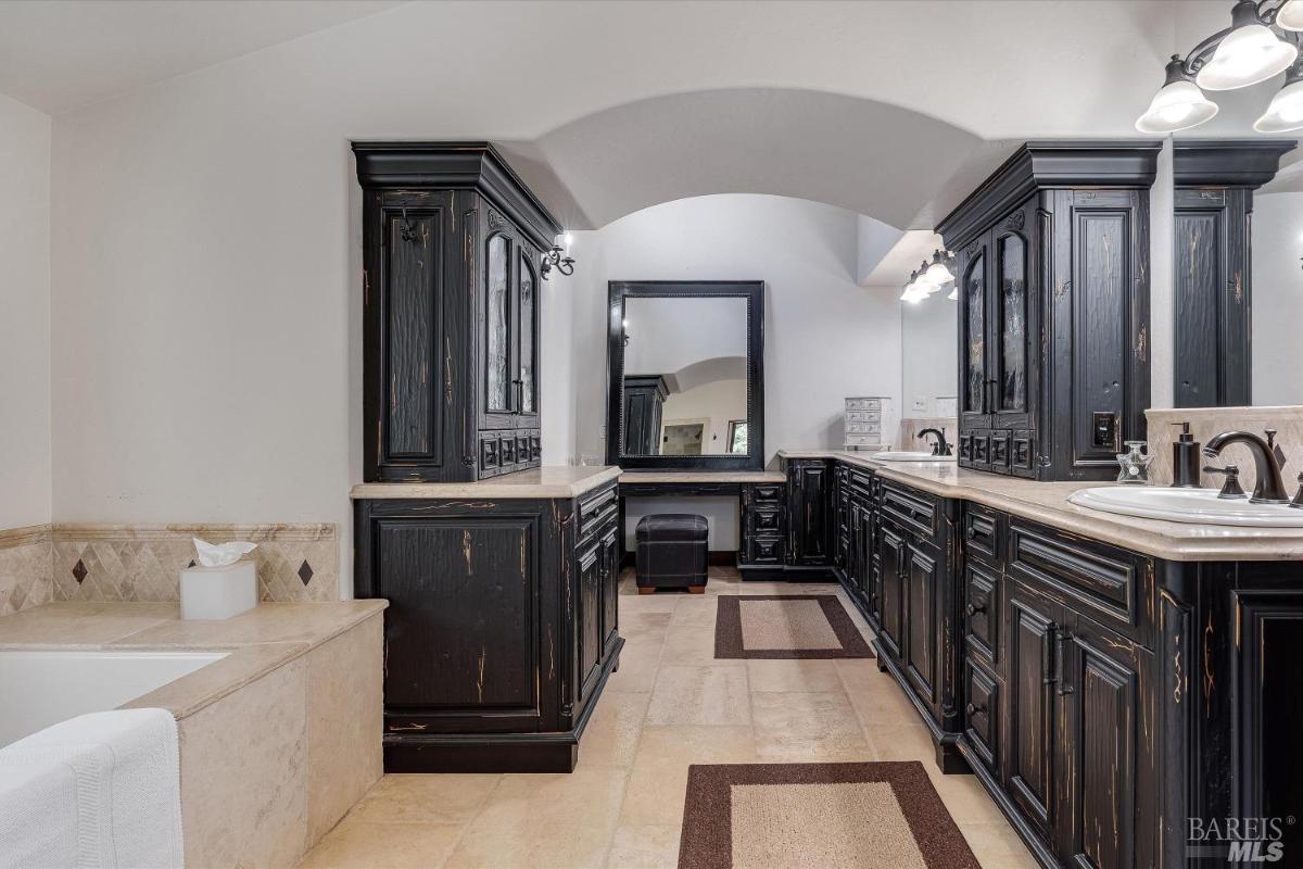 A bathroom with dark wood cabinets, double sinks, and a bathtub.