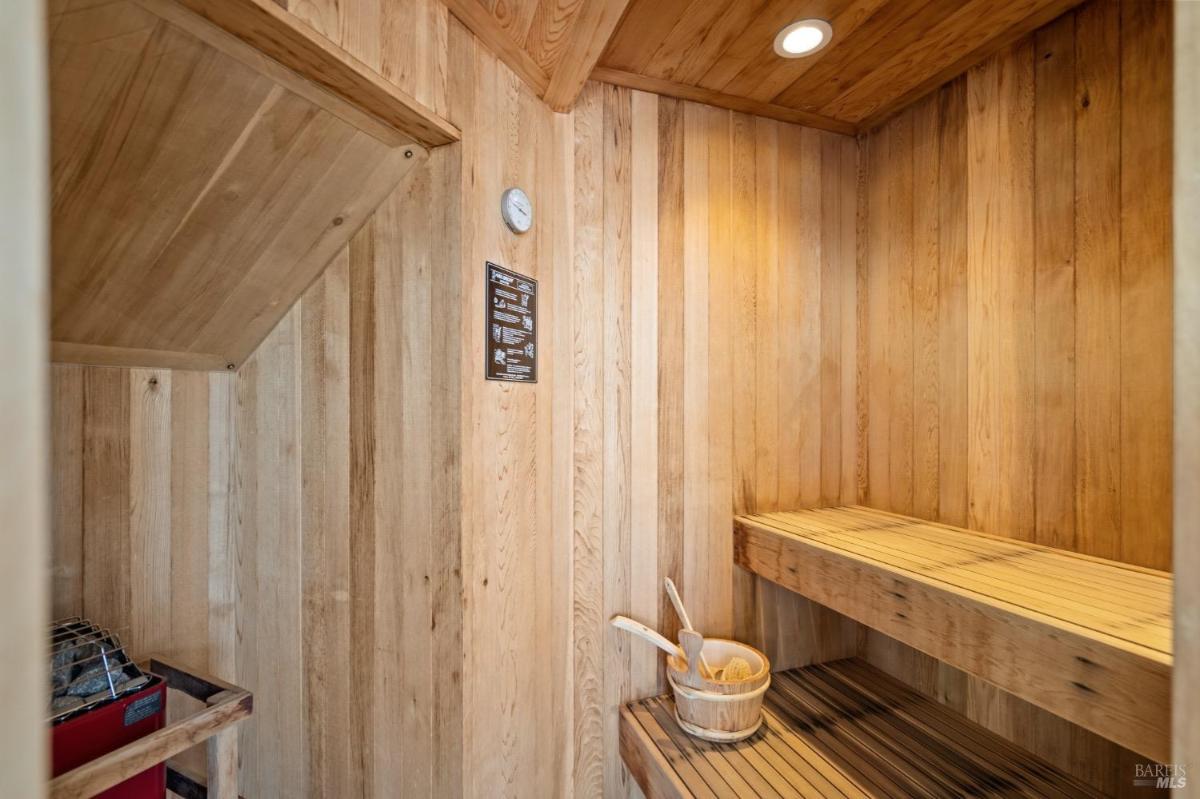 A compact sauna with wood-paneled walls, bench seating, and soft lighting for a warm, relaxing experience.