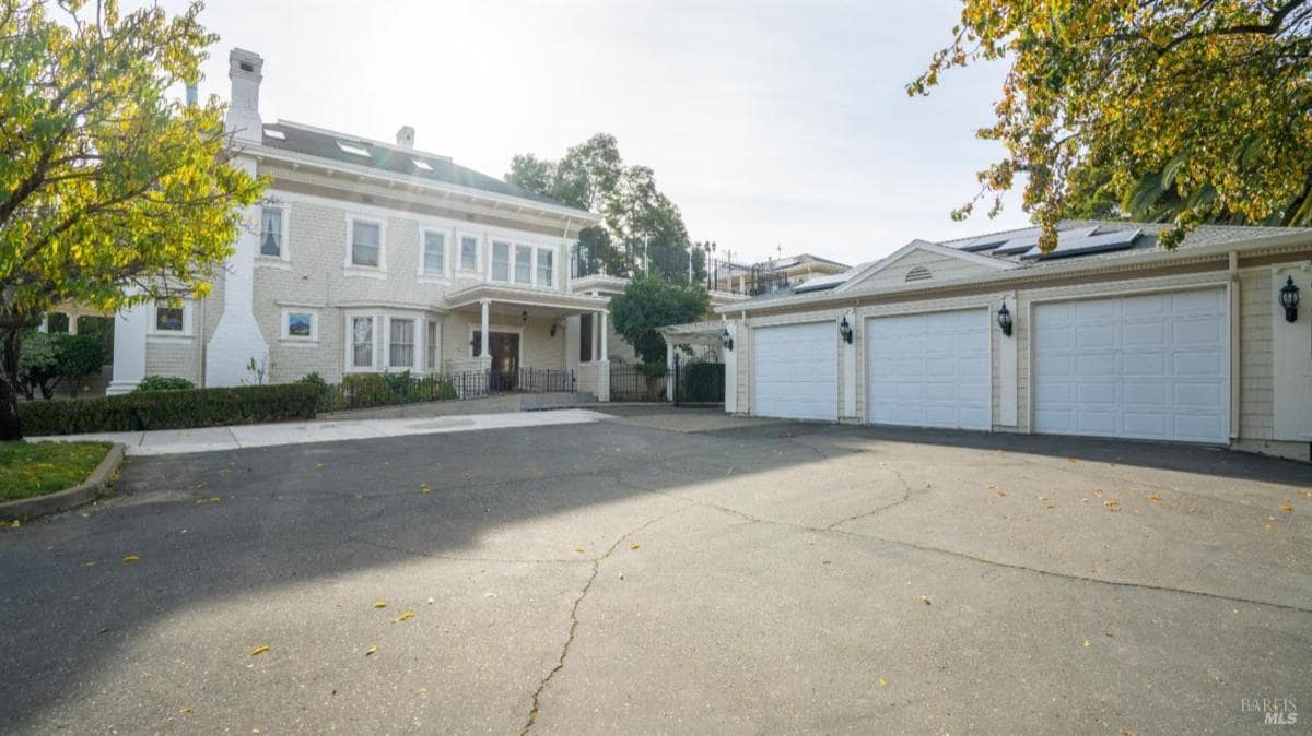 Exterior view of a large house with multiple garages and a paved driveway.