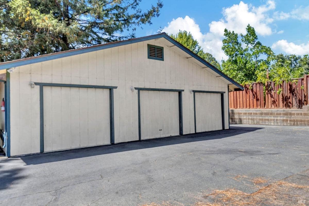 A detached garage with three doors and an asphalt driveway.