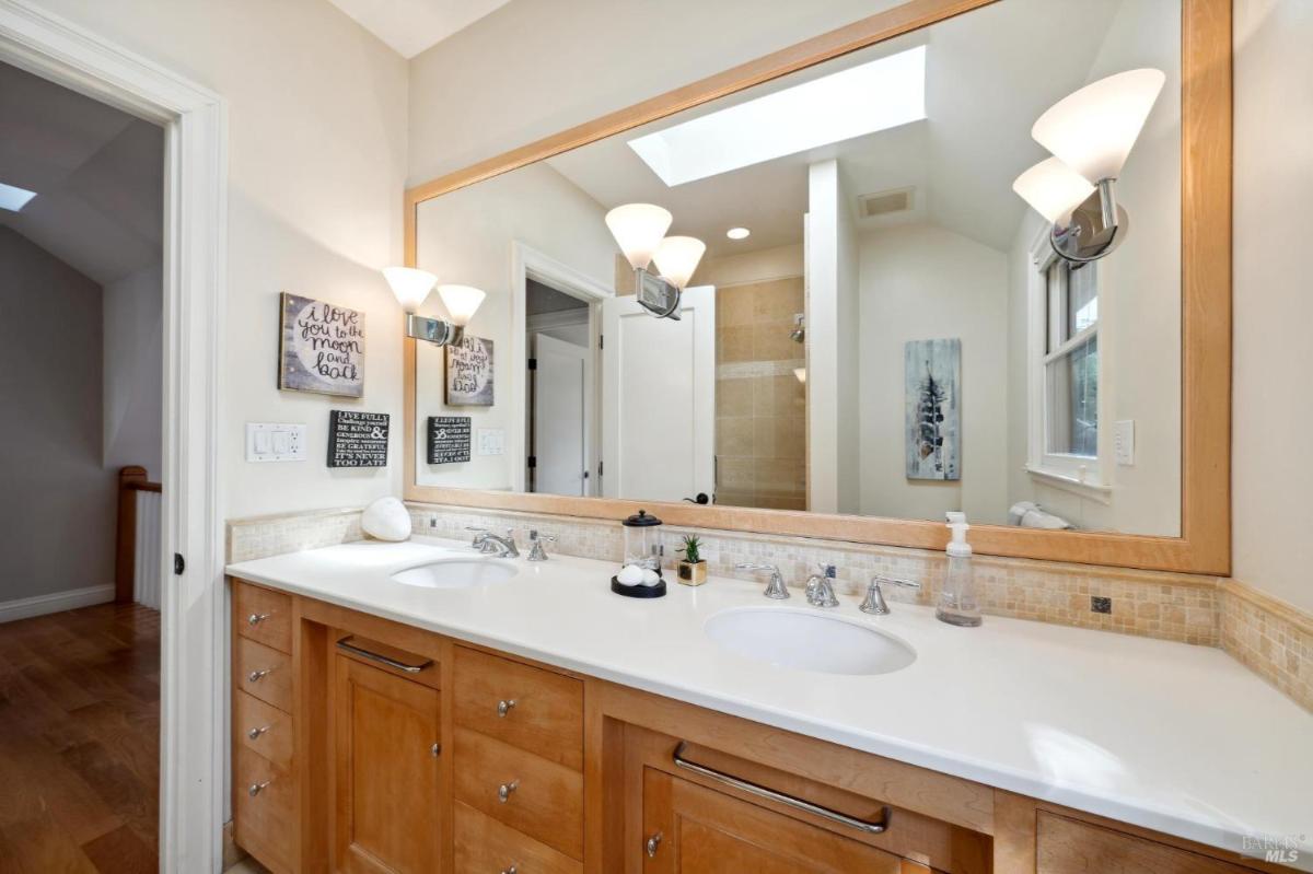 Bathroom with double sinks, large mirror, and overhead lighting.