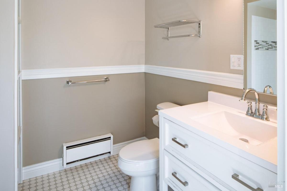 A bathroom with a white vanity, tiled floor, and a mounted towel rack.