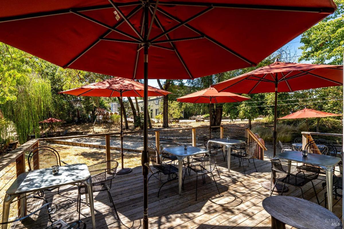 Deck with multiple tables, chairs, and red patio umbrellas.