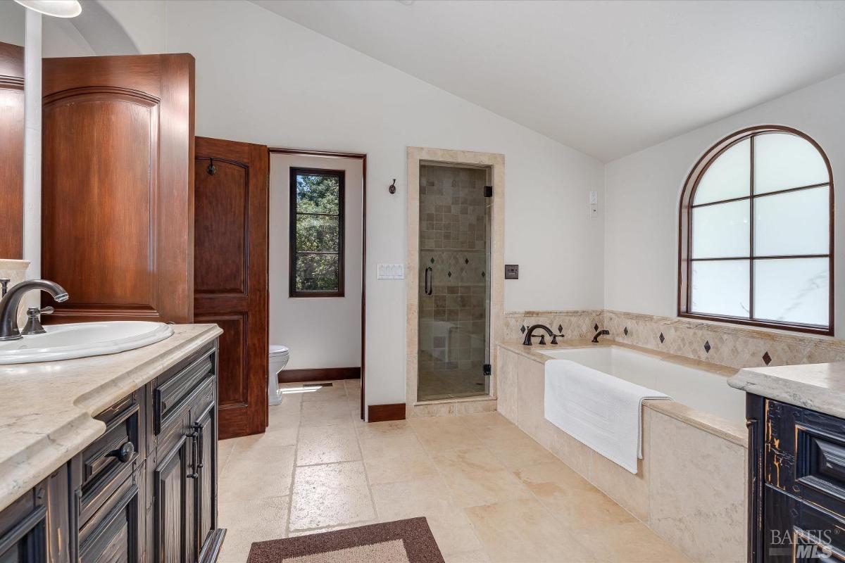 A bathroom with a bathtub, shower, and separate toilet area.