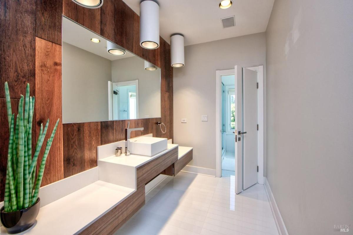 A bathroom with a long counter, sink, and mirror.