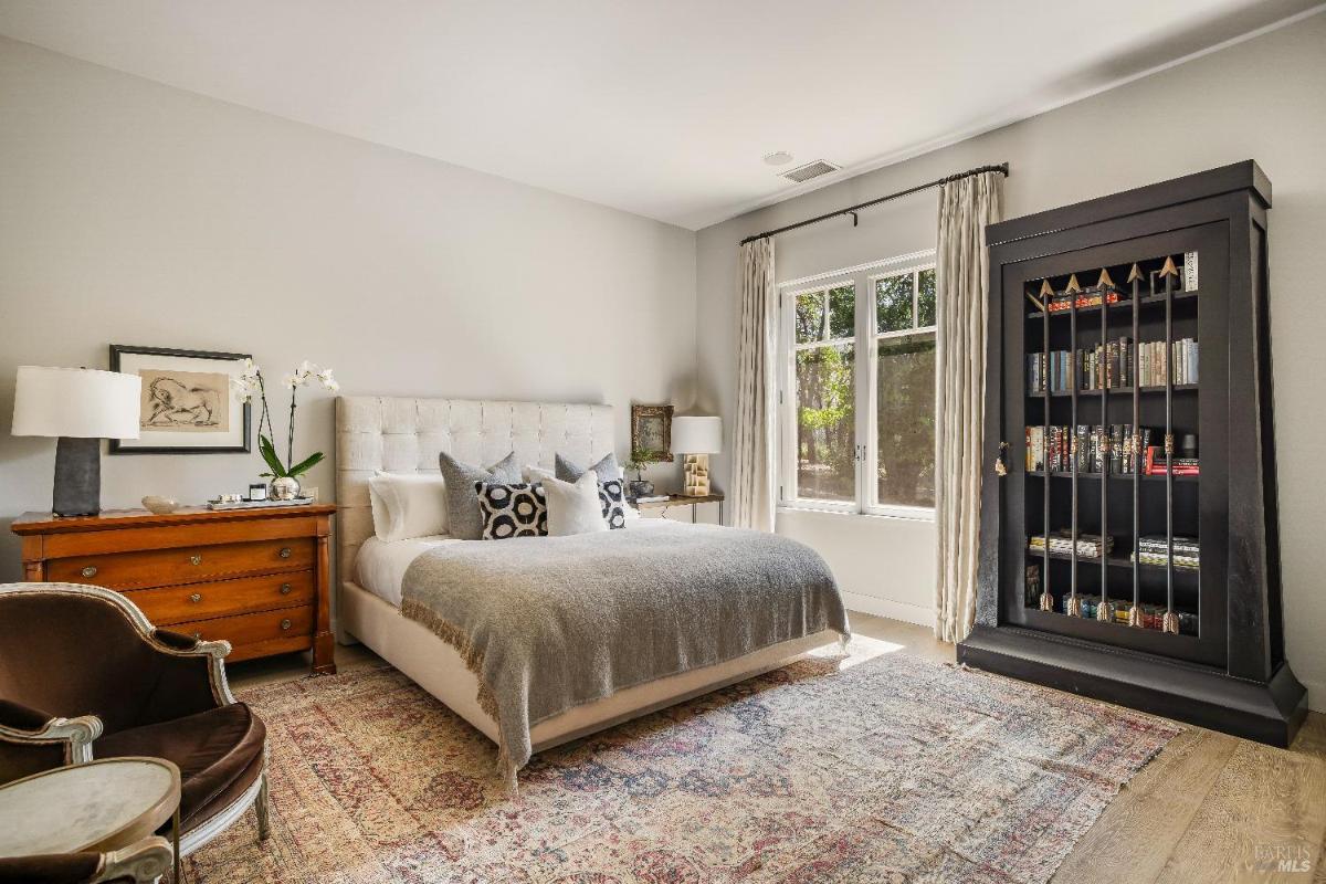 Bedroom with a vaulted ceiling, large windows, and access to a balcony.