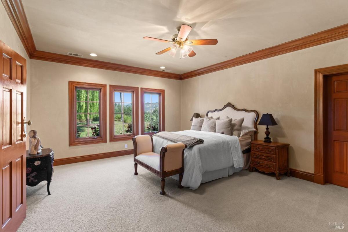 Bedroom with traditional decor, plush bedding, and garden-facing windows.