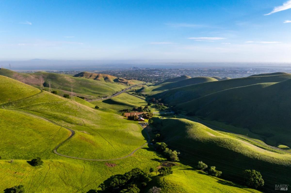 Panoramic view of hills and a distant city skyline under clear skies.