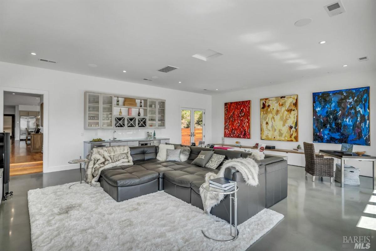 A family room with a sectional sofa, rugs, and colorful wall art. 