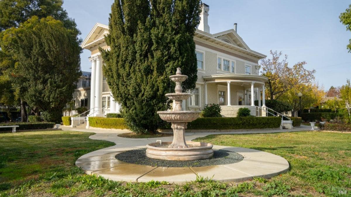 Side view of the house with a fountain and landscaped yard.