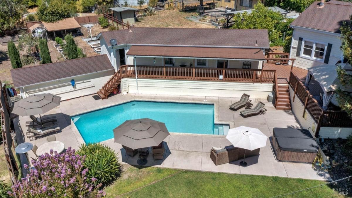 View of a swimming pool with surrounding deck, seating areas, and umbrellas.