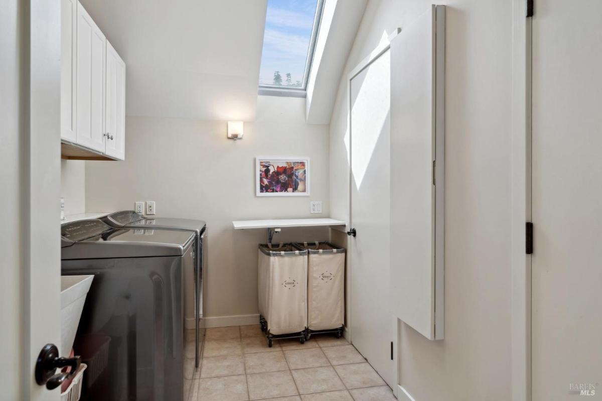 Laundry room with washer, dryer, skylight, and sorting bins.