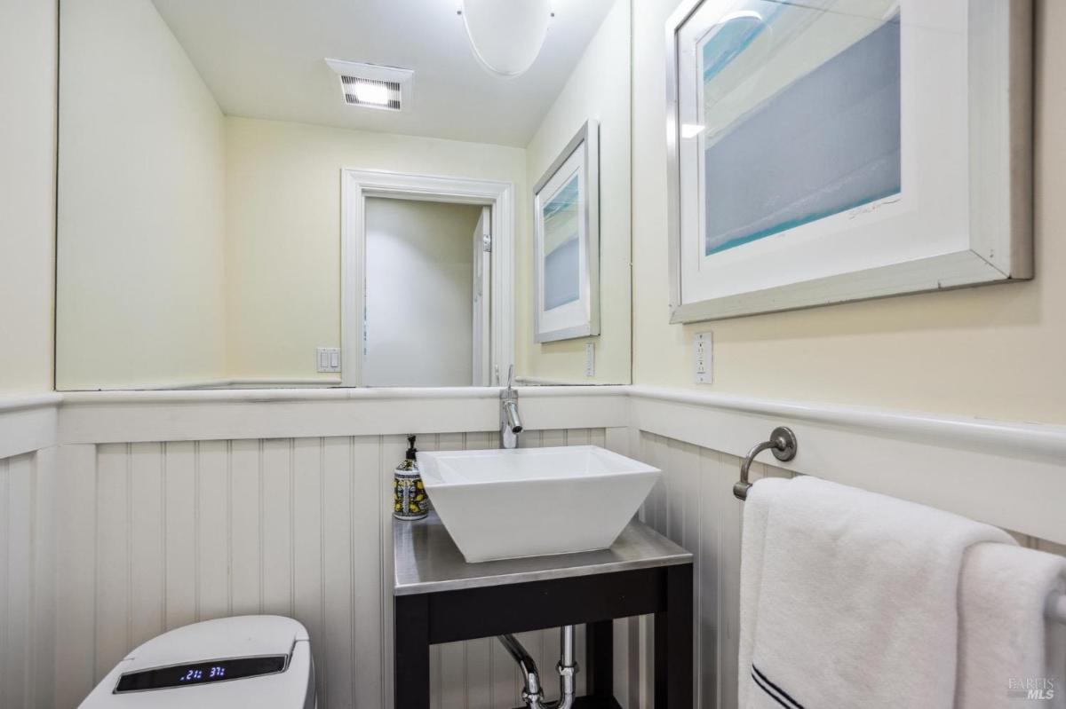 Powder room with a vessel sink on a metal stand, mirror, and towel rack.