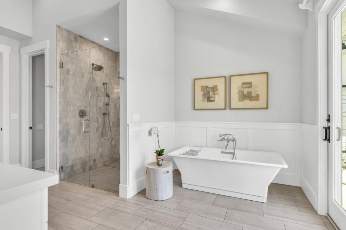 A spacious bathroom featuring a freestanding bathtub, a glass shower, and decorative wall art.