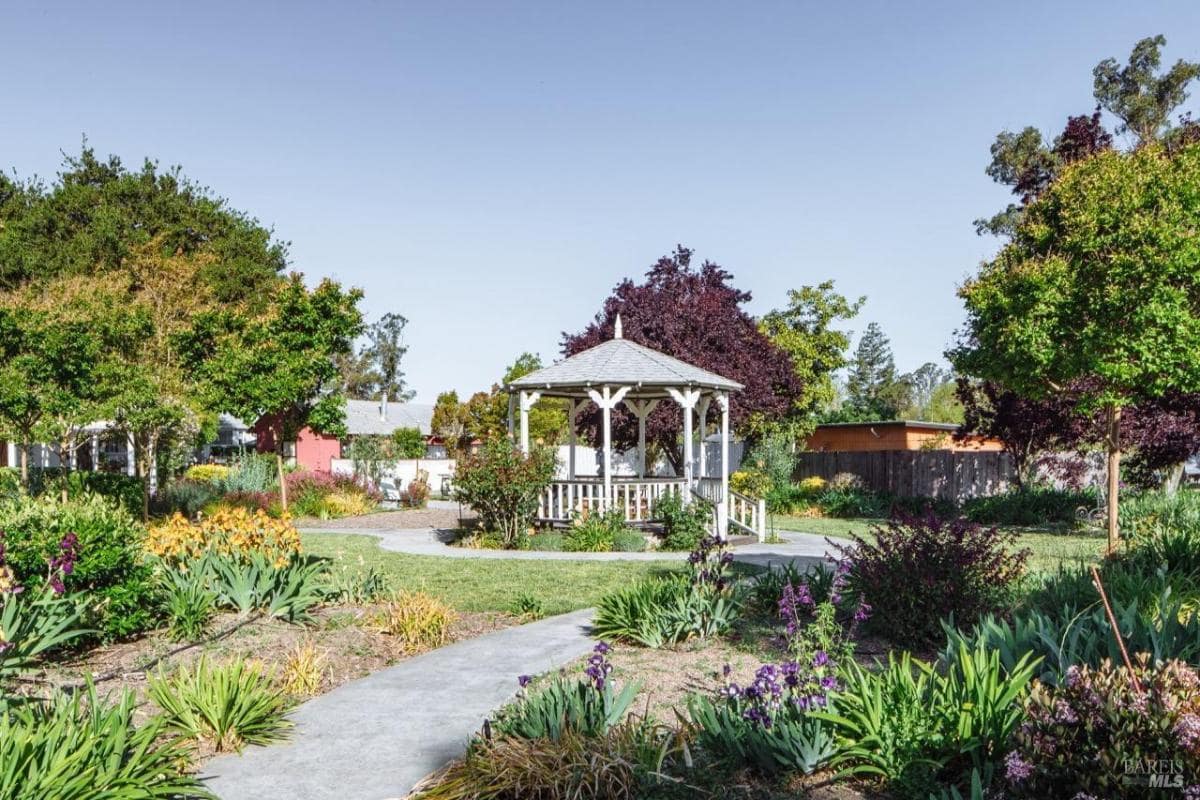 A gazebo surrounded by a landscaped garden with trees and flowers.